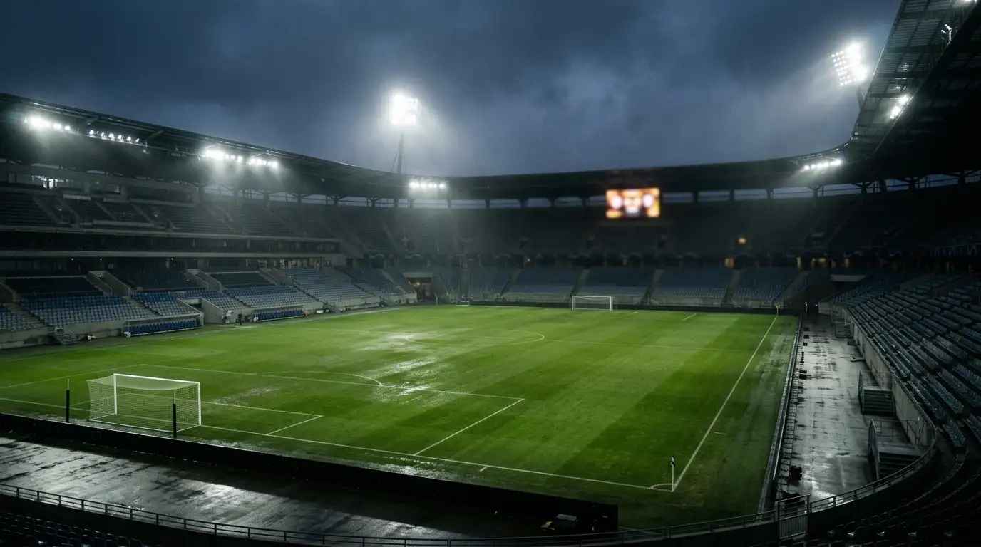 Ein leeres Fussballstadion am späten Abend nach einem K.-o.-Spiel, Flutlicht spiegelt sich auf dem nassen Rasen, Anzeigetafel im Hintergrund unscharf, ruhige Stimmung nach einem Verlängerungskrimi.
