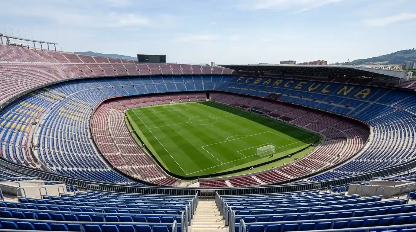 Ein leeres, offenes Fussballstadion bei Tageslicht von der oberen Tribüne aus, satter grüner Rasen, keine Zuschauer, klare Linien – ruhige Atmosphäre vor der entscheidenden Turnierphase.